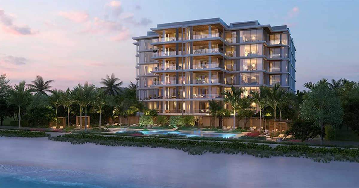 Oceanfront luxury condominium building illuminated at sunset with palm trees