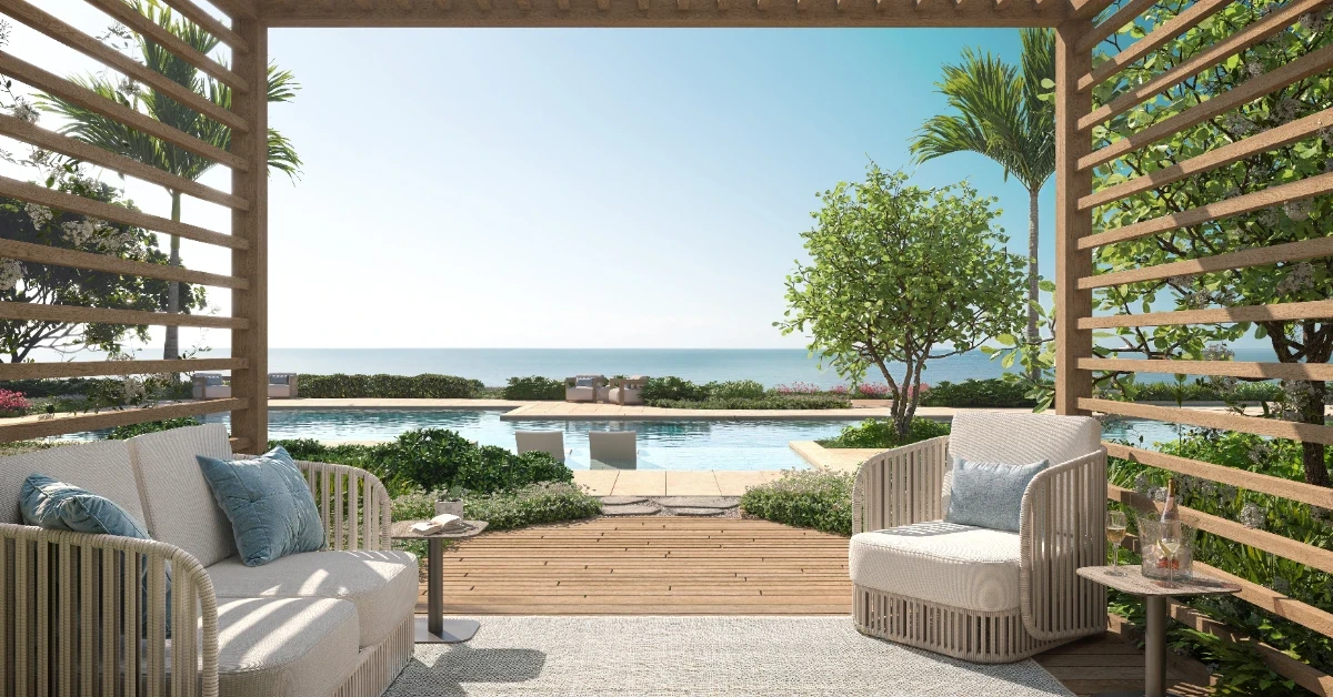 Shaded poolside cabana with lounge chairs overlooking a pool and the ocean.