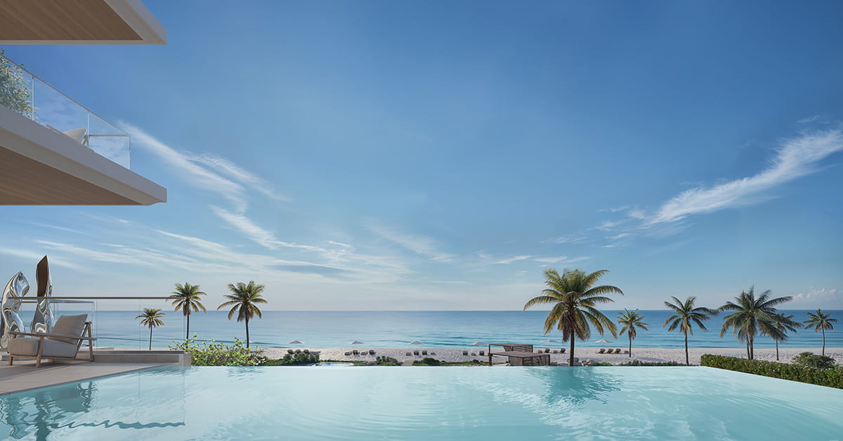 Infinity pool overlooks a sandy beach and calm blue ocean under a clear sky, with palm trees along the shore.